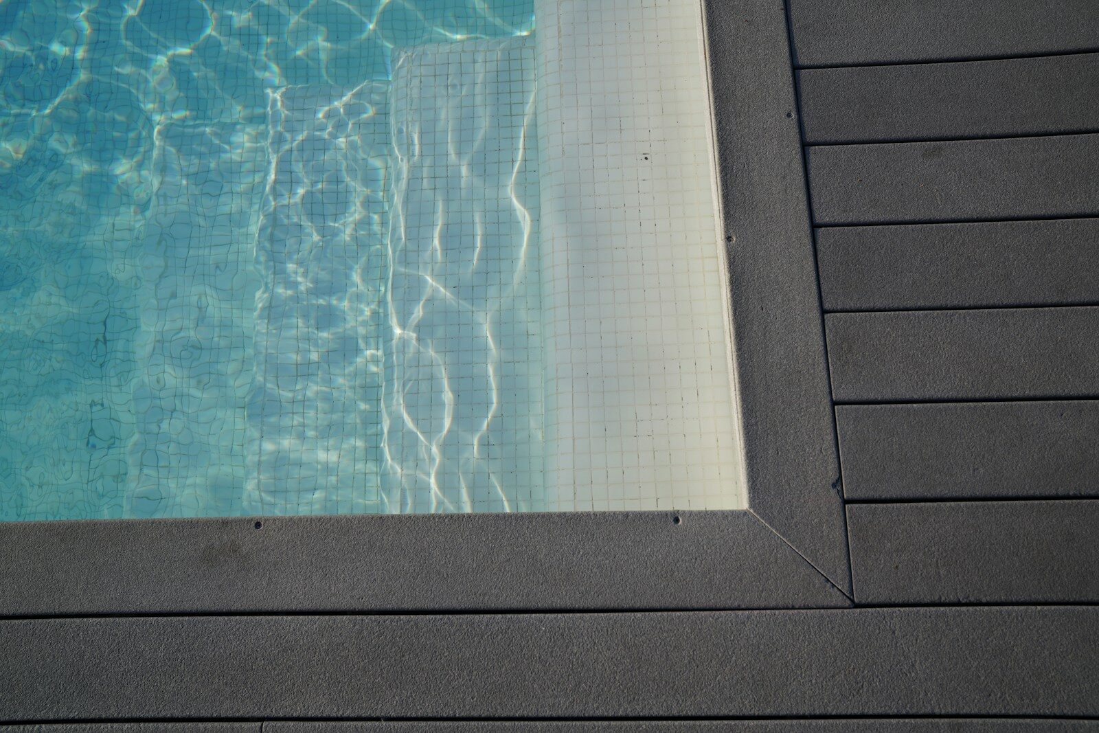 Rippling blue water in a swimming pool with deck